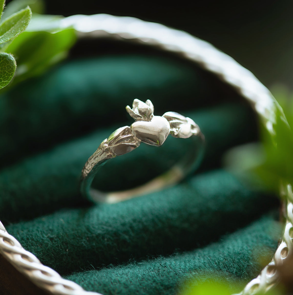 Vista laterale dell'anello Claddagh in argento 925, con dettagli botanici che abbracciano il cuore.