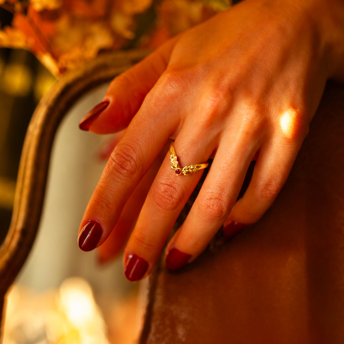 Anello Foglia d'Autunno in oro giallo 18 kt con granato rosso indossato sulla mano, con dettagli ispirati alle foglie di quercia.