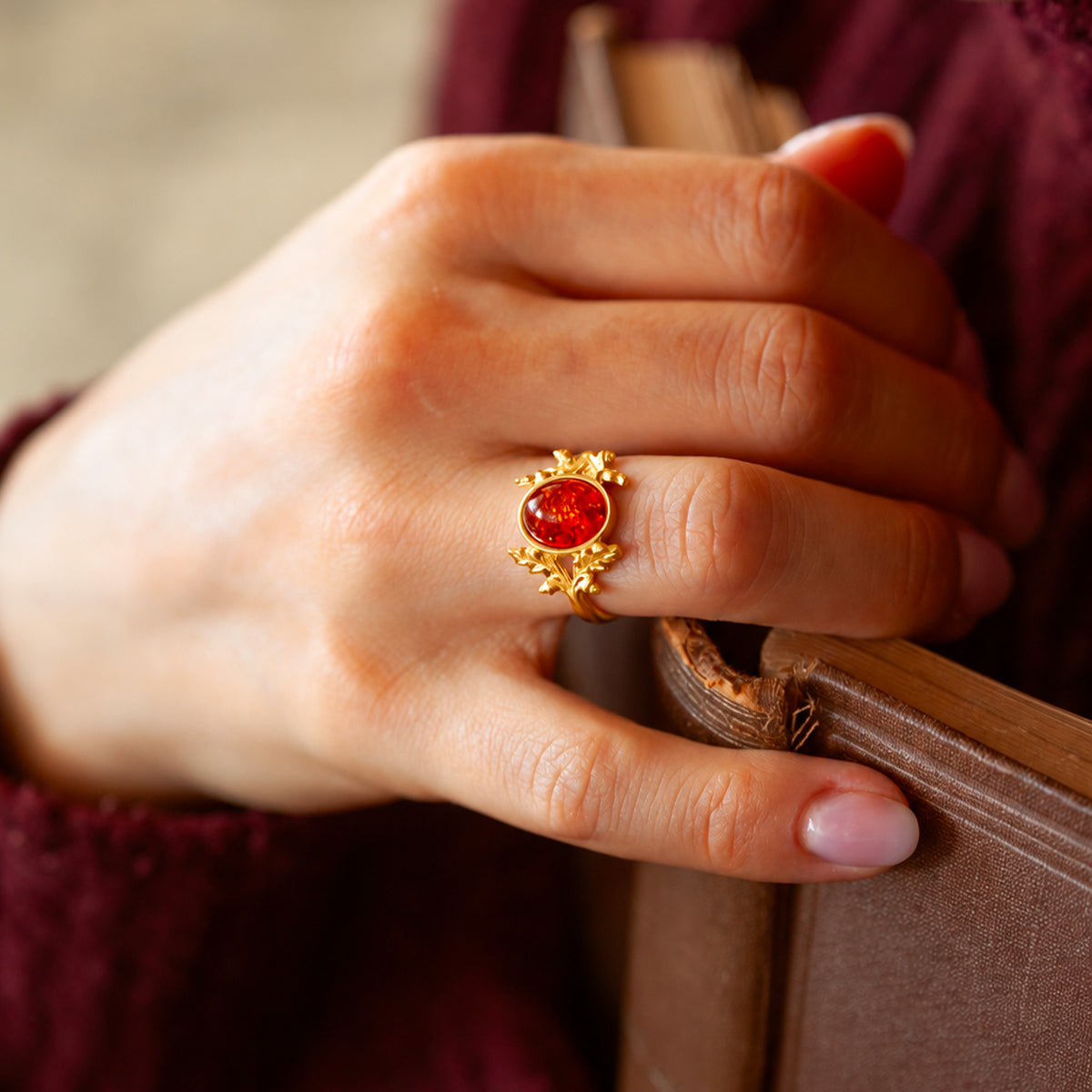 Anello Quercia in oro giallo 18 kt con ambra baltica indossato sulla mano, con dettagli di foglie e ghiande ispirati ai boschi.
