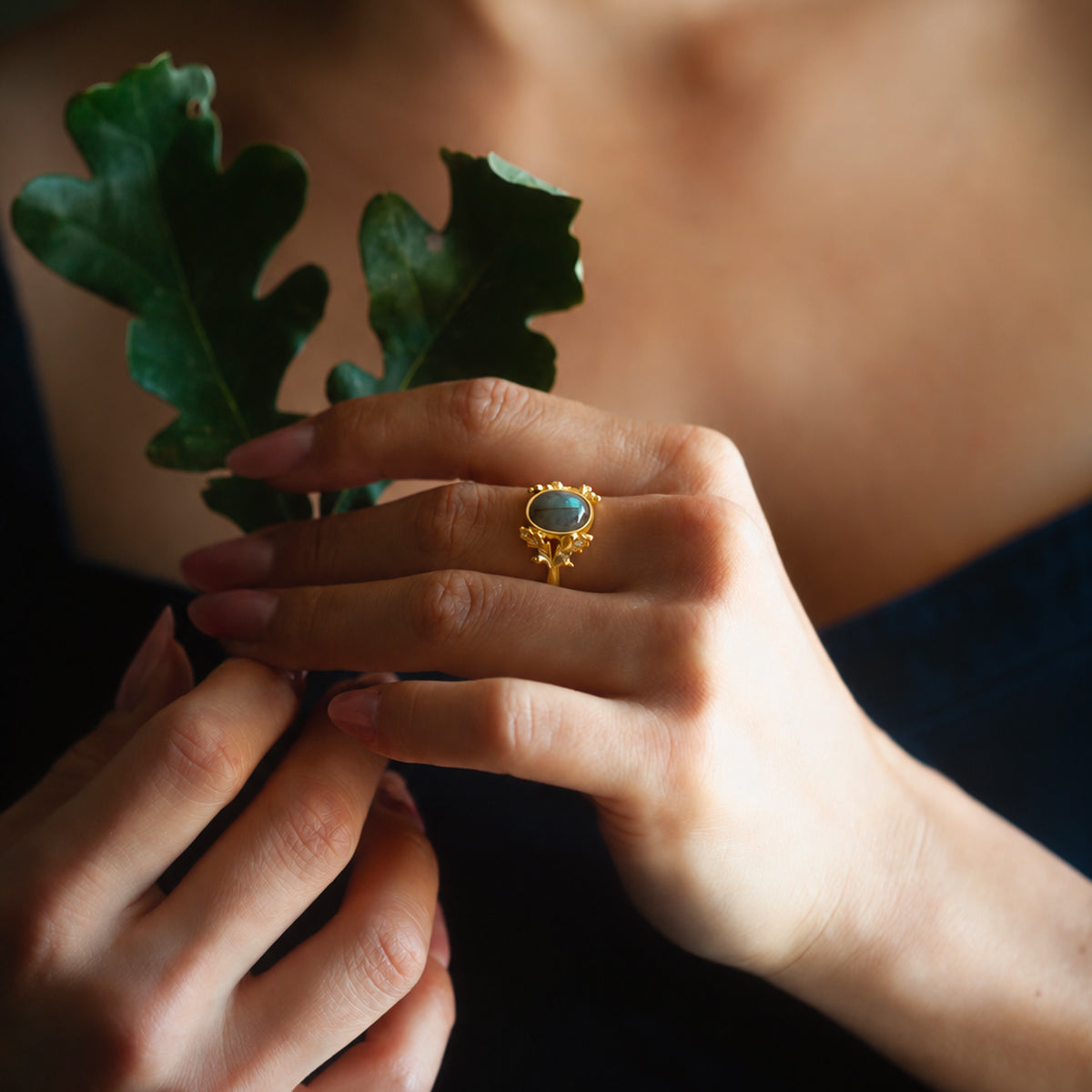 Anello Quercia in oro giallo 18 kt con labradorite indossato sulla mano, con dettagli artigianali di foglie e ghiande.